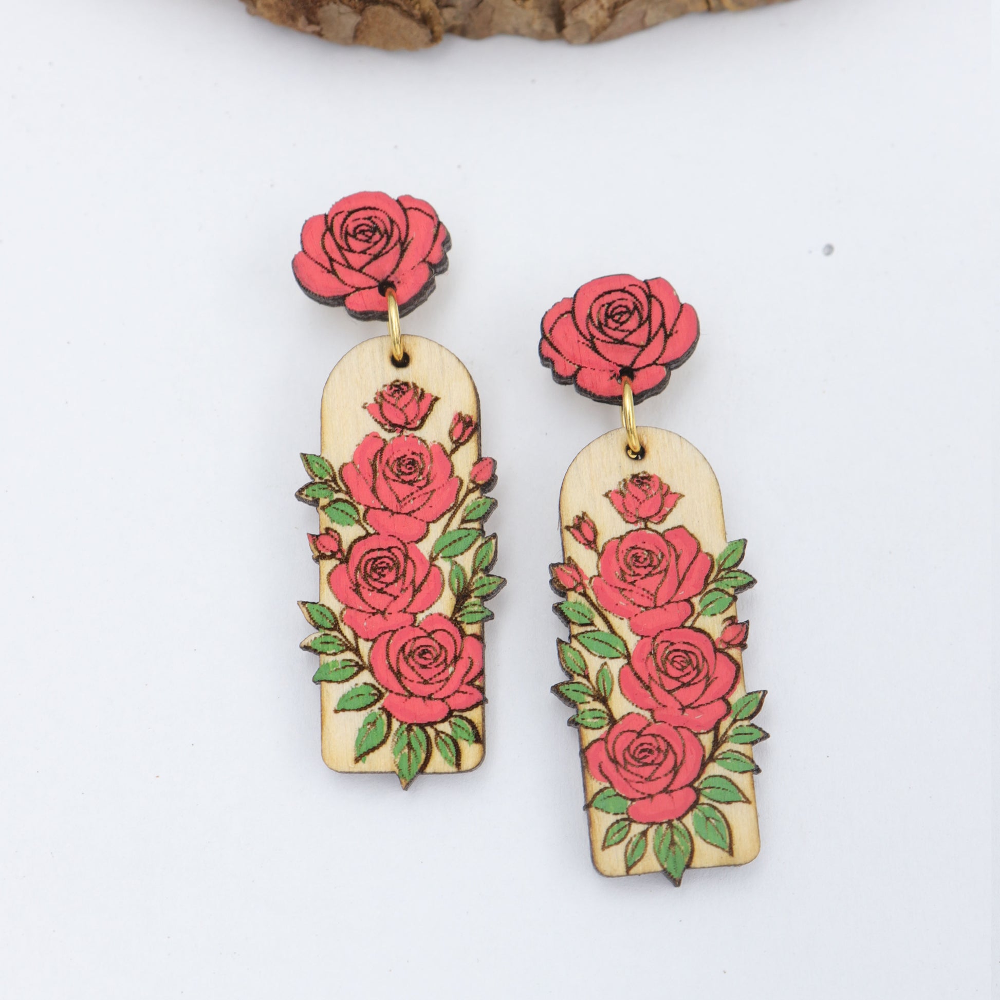 Pair of earrings with red rose designs on a white background