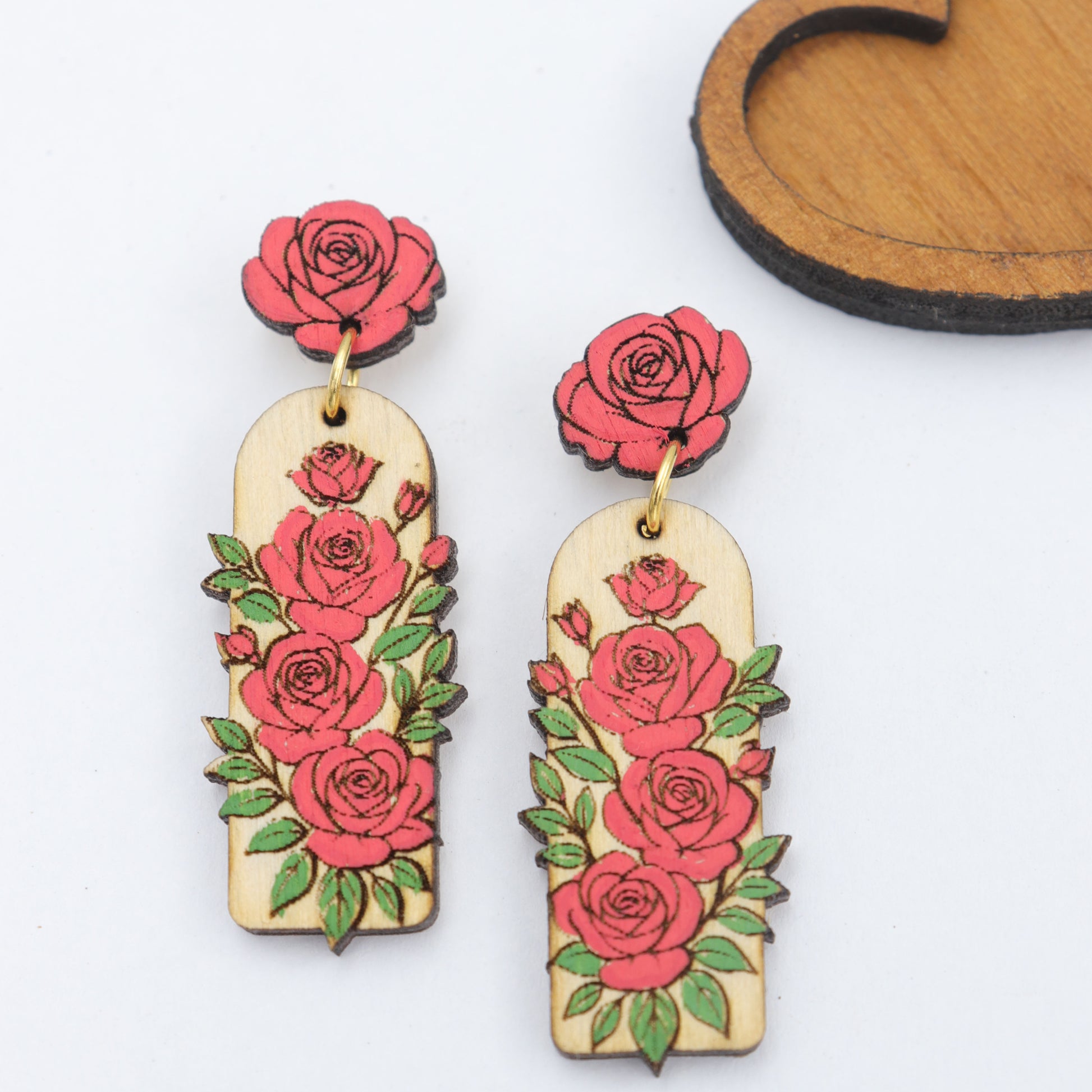 Pair of floral earrings with red roses on a white background
