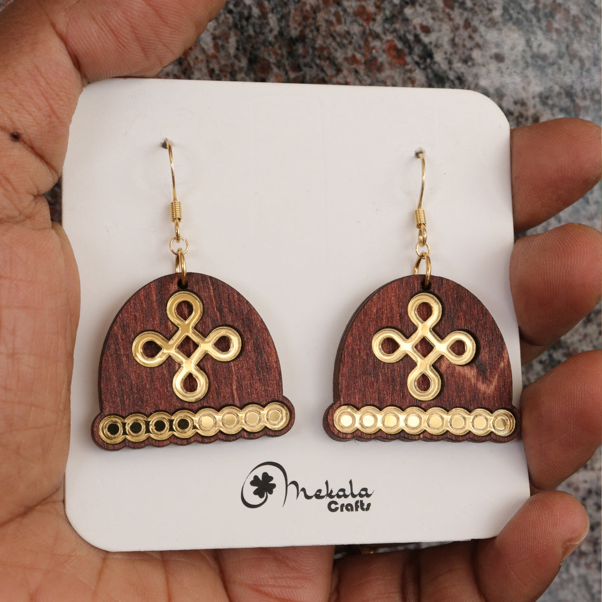 Close-up of dome-shaped wooden earrings with gold kolam knot design and beaded trim, handmade by Mekala Crafts