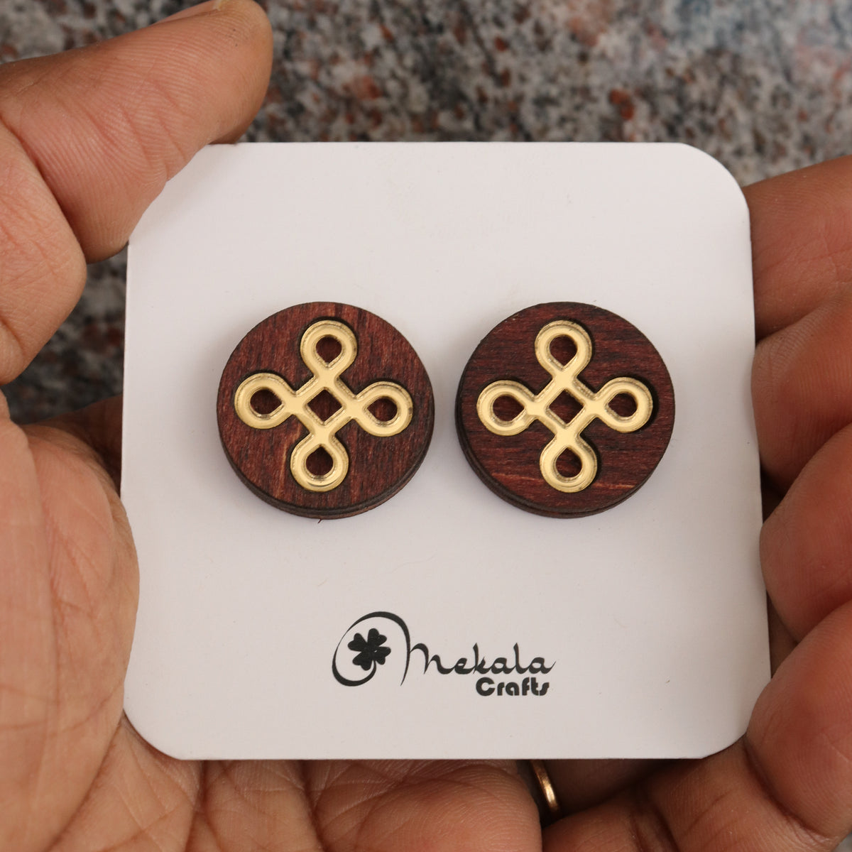 Close-up of round-shaped kolam knot wooden stud earrings with gold inlay, handmade by Mekala Crafts