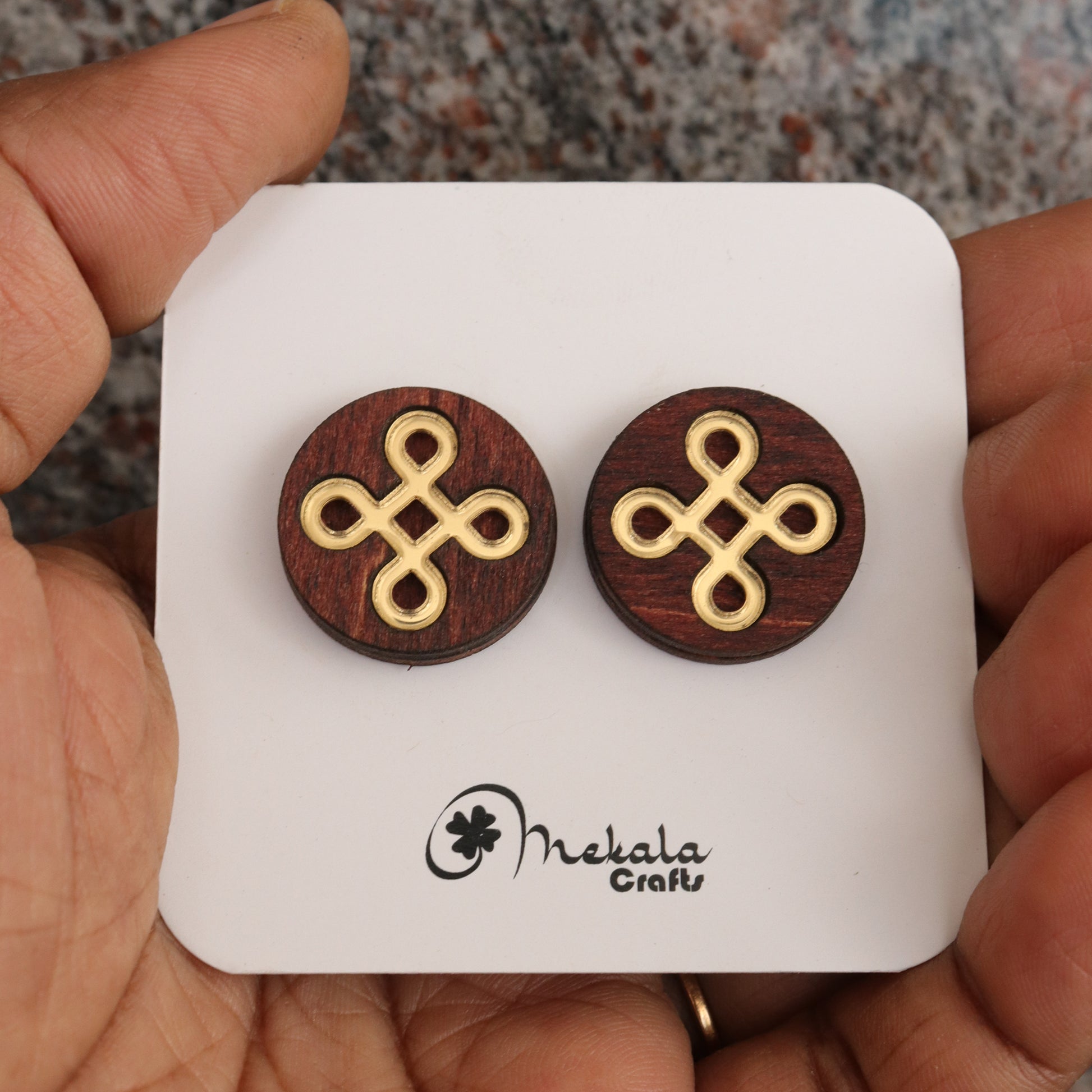 Close-up of round-shaped kolam knot wooden stud earrings with gold inlay, handmade by Mekala Crafts