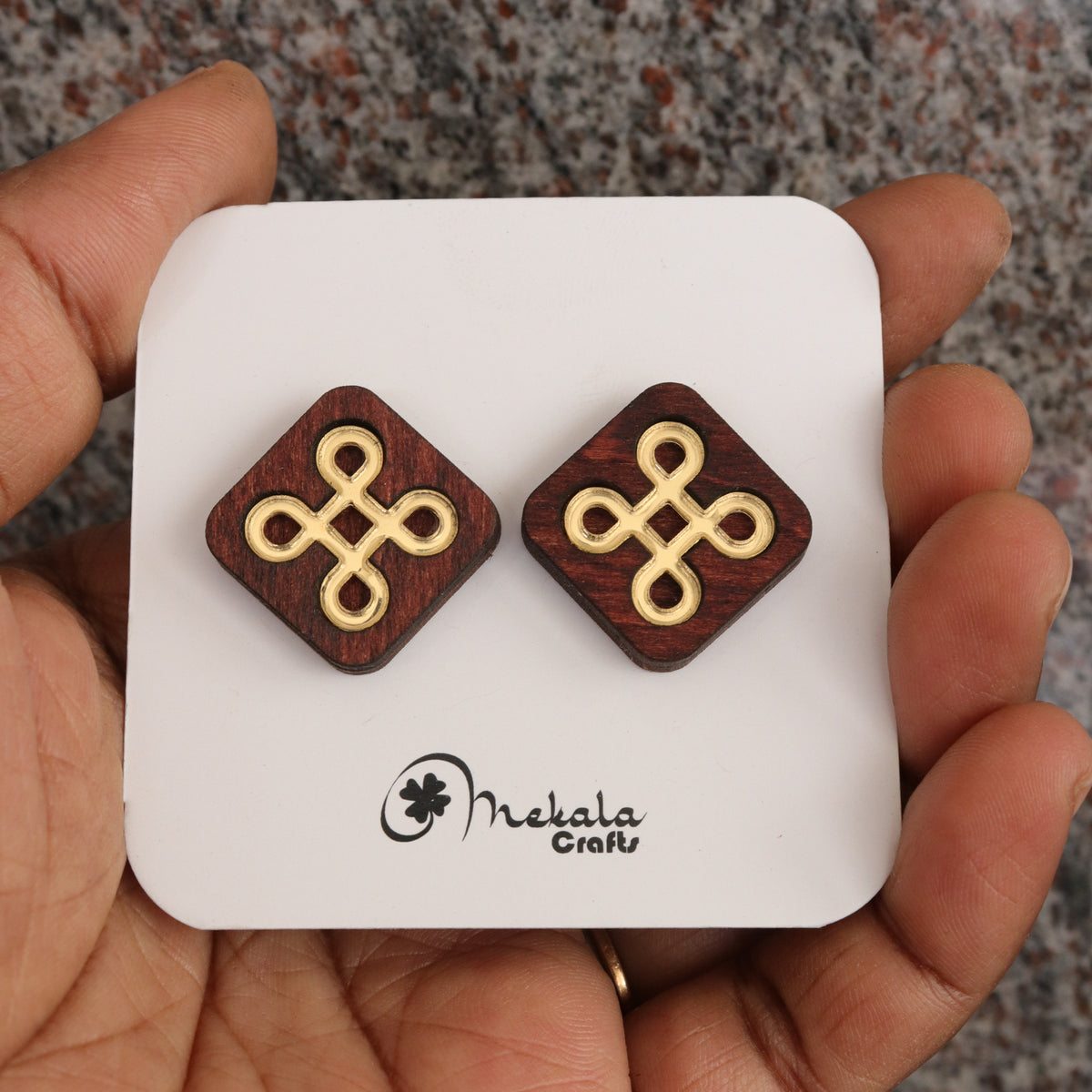 Close-up of diamond-shaped kolam knot wooden stud earrings with gold inlay, handmade by Mekala Crafts