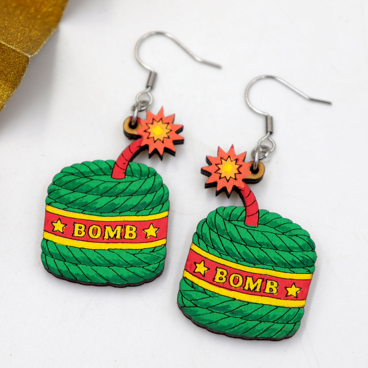Hand-painted wooden Diwali green bomb cracker dangle earrings with red fuse and starburst, handmade by Mekala Crafts