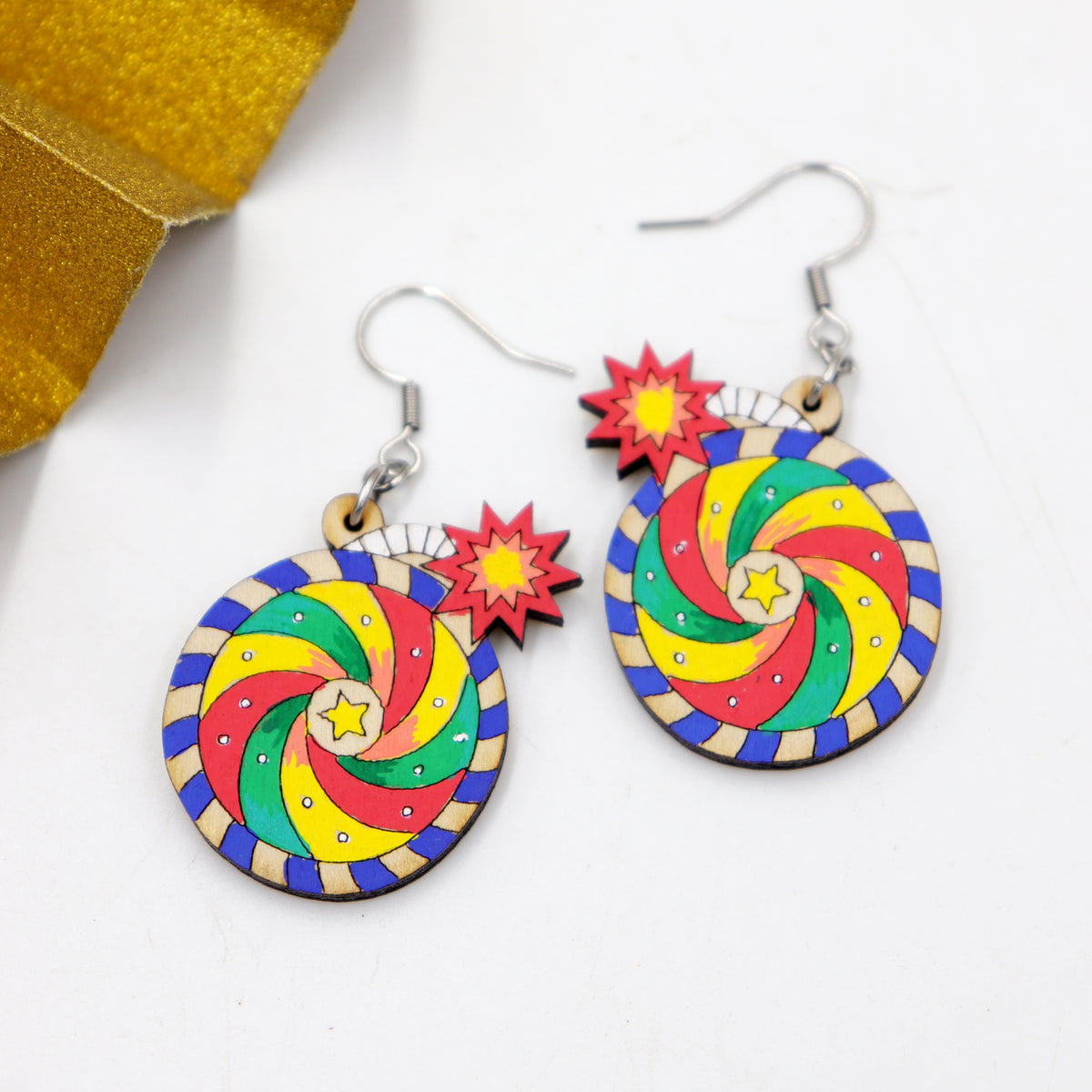 Hand-painted wooden Diwali chakkar spinning wheel cracker dangle earrings with colorful swirl and starburst, handmade by Mekala Crafts