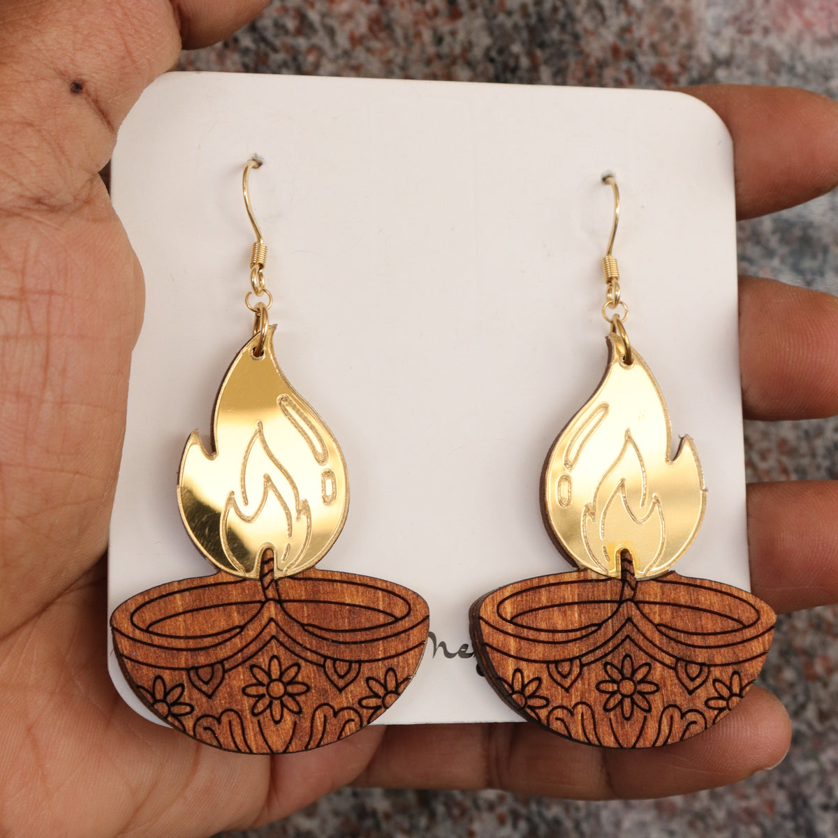 Close-up of wooden diya lamp earrings with gold mirrored flame and floral engraving, handmade by Mekala Crafts